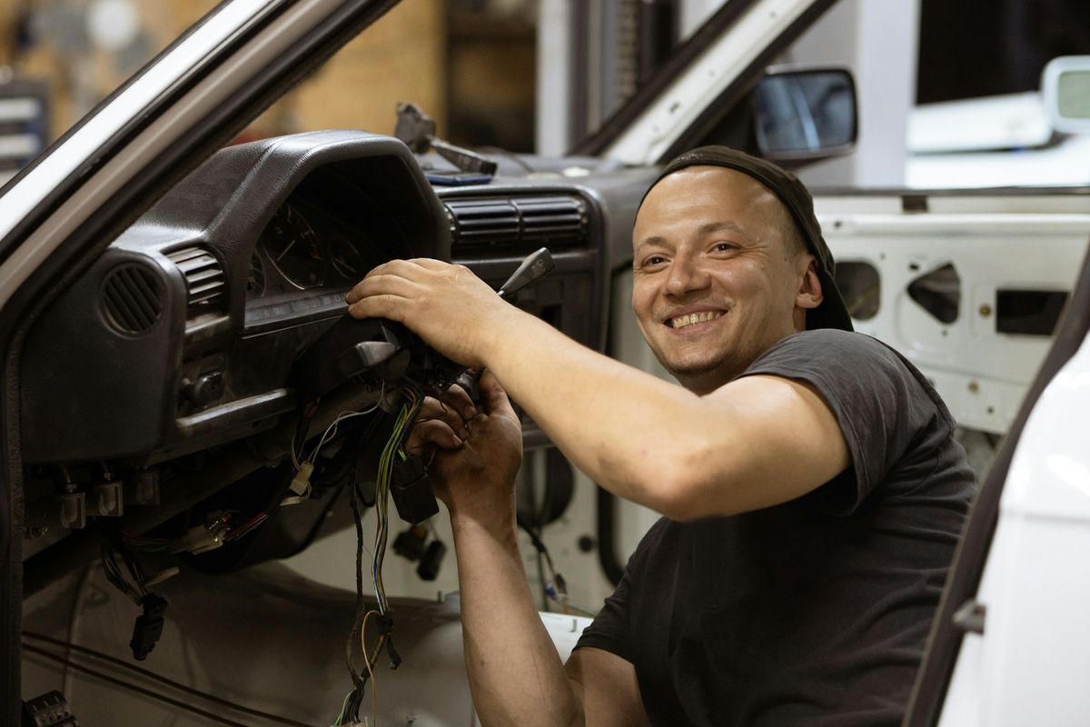 Een mecanicien werkt aan de bedrading achter het dashboard van een wagen